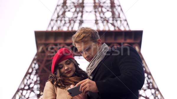 Male and female tourists searching destination in Paris on map in mobile app Stock photo © motortion