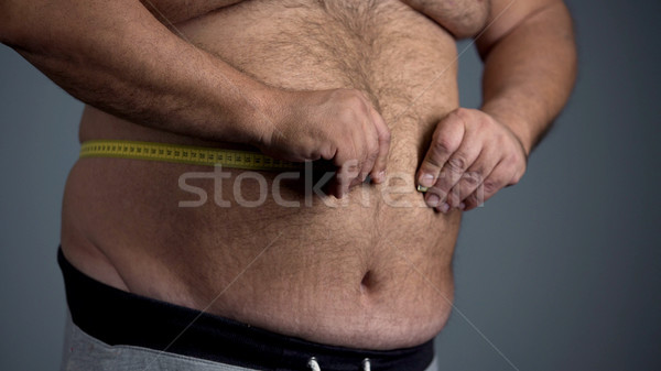 Sad overweight man unable to measure his waist, fat tummy with stretch marks Stock photo © motortion