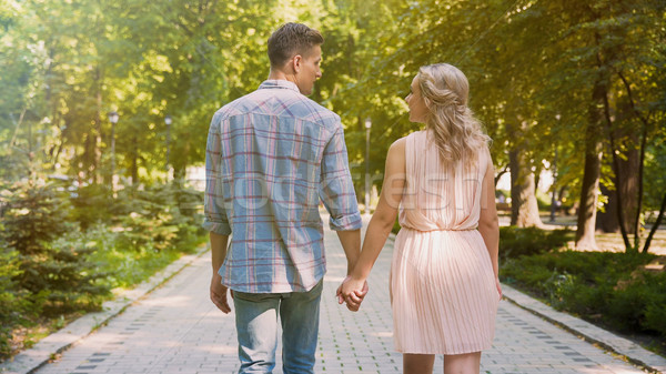 Couple in love strolling through beautiful summer park, gently holding hands Stock photo © motortion