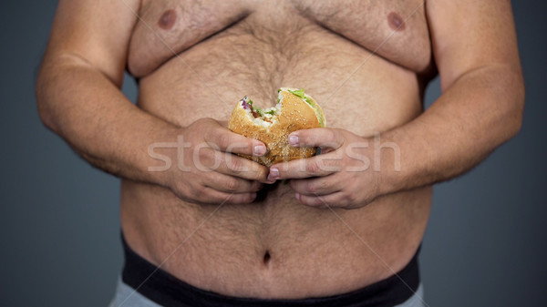 Elhízott férfi tart egészségtelen hamburger kezek Stock fotó © motortion