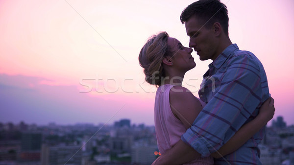 Handsome guy tenderly embracing his beautiful lady on open terrace, cityscape Stock photo © motortion