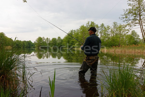 Foto stock: Pescador · pie · lago · peces · nublado · día