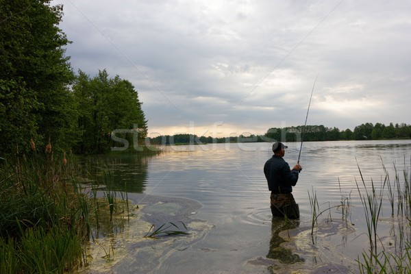 Pescatore piedi lago pesce nuvoloso giorno Foto d'archivio © mtmmarek