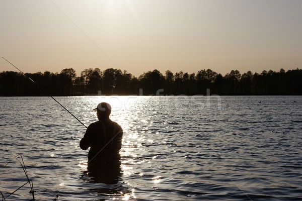 Pescatore silhouette piedi lago pesce Foto d'archivio © mtmmarek