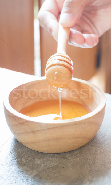 Hand on honey dipper from wooden cup Stock photo © nalinratphi