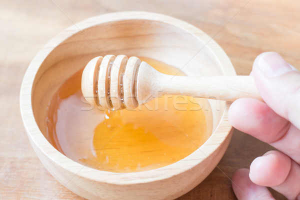 Hand on honey dipper from wooden cup Stock photo © nalinratphi