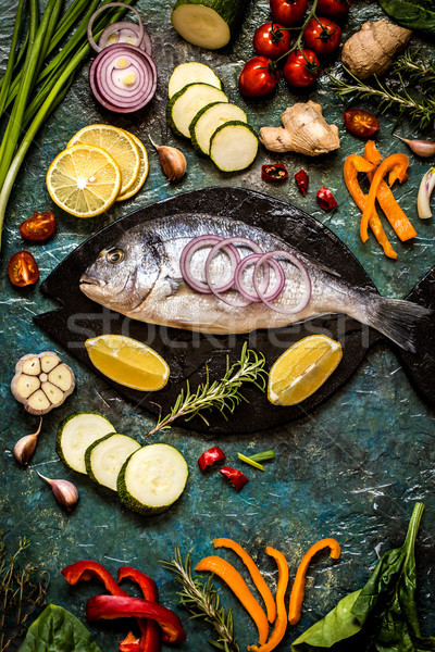 Dorada fish with vegetables, lemon and herbs on a blue background Stock photo © Natalya_Maiorova