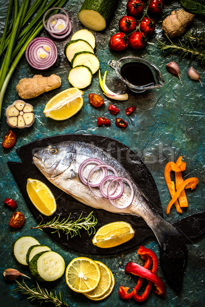 Dorada fish with vegetables, lemon and herbs on a blue background Stock photo © Natalya_Maiorova