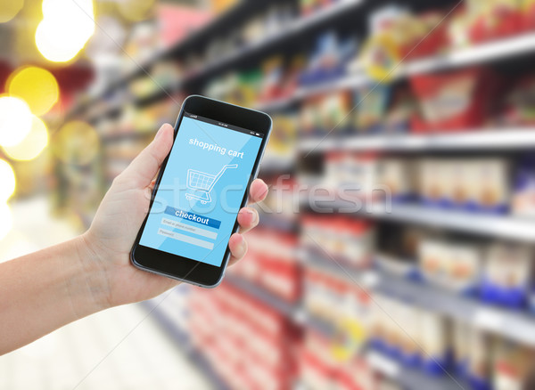 hand holding a modern smartphone in supermarket Stock photo © neirfy