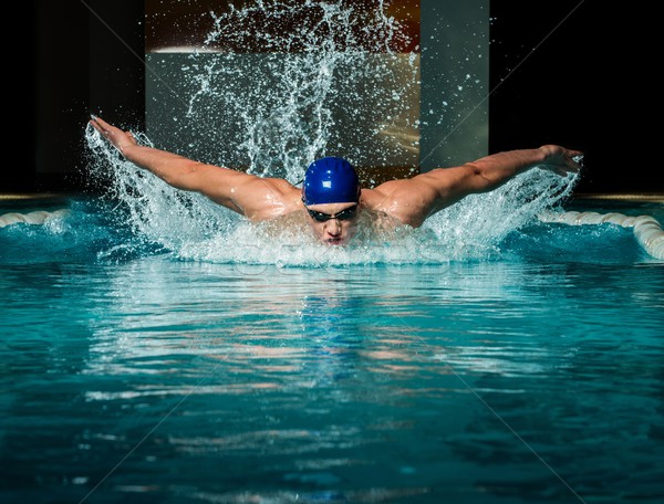 Muscular young man in blue cap in swimming pool Stock photo © Nejron