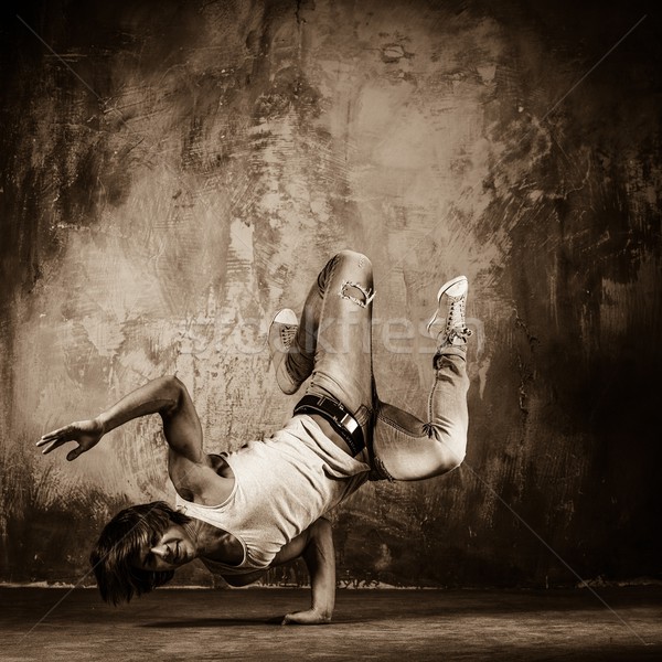 Toned picture of young man  doing acrobatic movements against grunge wall Stock photo © Nejron