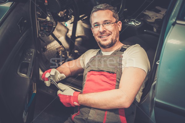 Cheerful mechanic with wrench fixing something in a car interior  Stock photo © Nejron