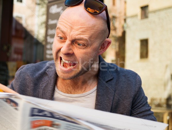 MIddle-aged man becoming enraged while reading newspaper outdoors Stock photo © Nejron