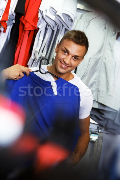 Handsome young man choosing sports wear in a sport outlet Stock photo © Nejron