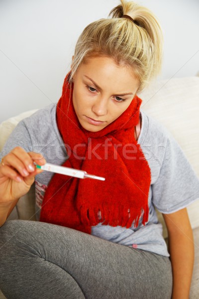 Sick young woman with thermometer at home Stock photo © Nejron