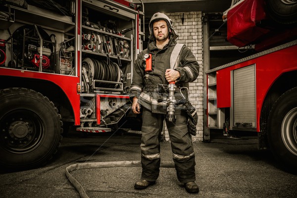 Firefighter near truck with equipment with water water hose over shoulder  Stock photo © Nejron