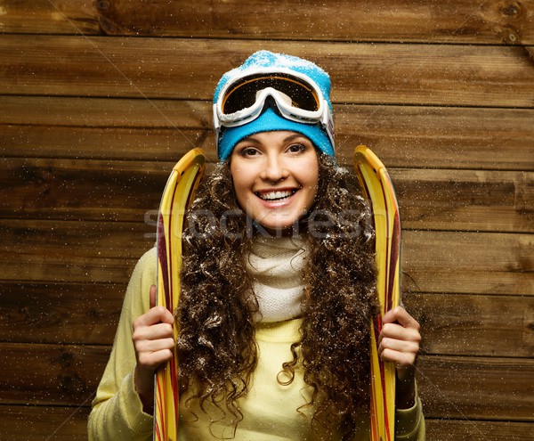 Smiling woman with skies standing against wooden house wall under snow Stock photo © Nejron