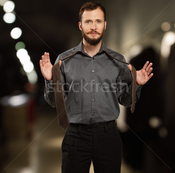 Handsome man with beard tying a tie in a clothing store Stock photo © Nejron