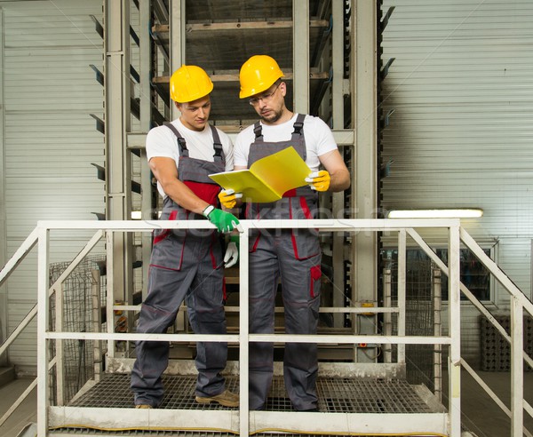 Two positive workers  in safety hats on a factory Stock photo © Nejron