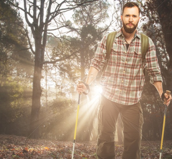 Handsome traveler with backpack and hiking poles in autumnal forest Stock photo © Nejron