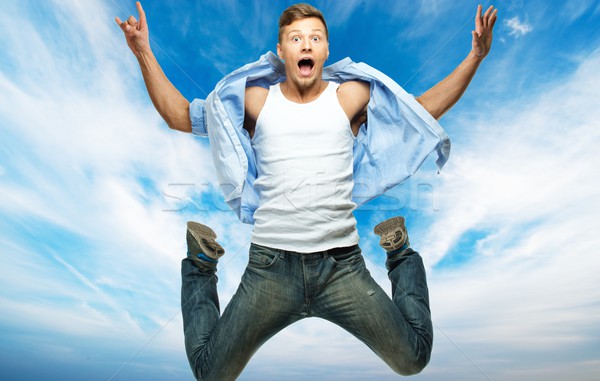 Funny man in blue shirt and jeans jumping against blue sky Stock photo © Nejron