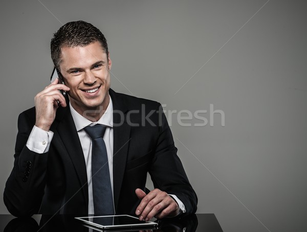 Well-dressed man in black suit with mobile phone and tablet pc Stock photo © Nejron