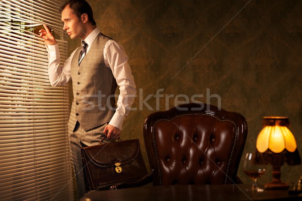 Retro man with a briefcase looking through jalousie. 
 Stock photo © Nejron
