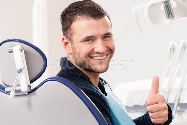 Smiling young man at dentist's surgery with thumb up Stock photo © Nejron