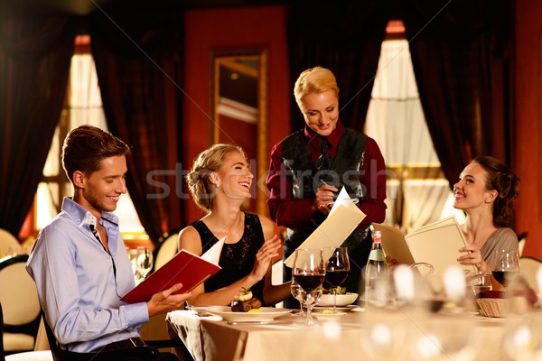 Stock photo: Group of young friends with menus choosing in a luxury restaurant