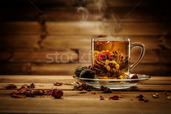 Glass cup with tea flower against wooden background Stock photo © Nejron