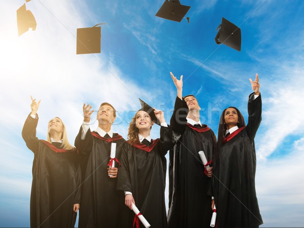 Stock photo: Happy multi ethnic group of graduated young students throwing hats in the air