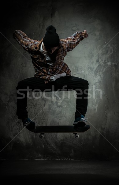 Young man in hat and shirt performing jump on skateboard Stock photo © Nejron