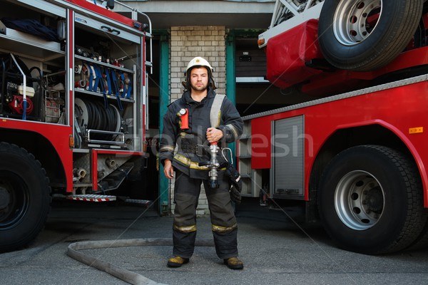 Firefighter near truck with equipment with water water hose over shoulder  Stock photo © Nejron