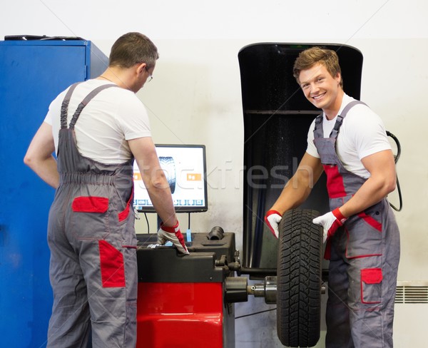 Two mechanics balancing wheel in a car workshop Stock photo © Nejron