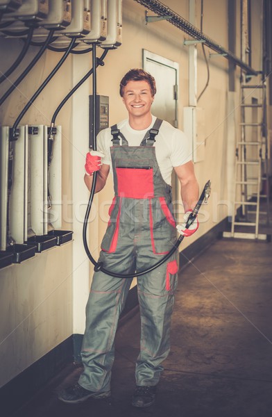Cheerful serviceman holding hose with unbottled motor oil in a car workshop Stock photo © Nejron