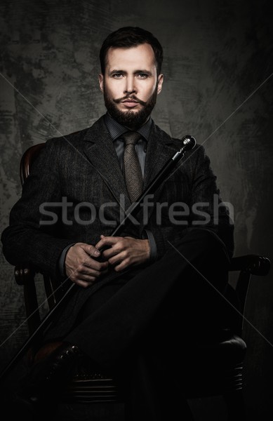 Stock photo: Handsome well-dressed man with walking stick sitting in leather chair 