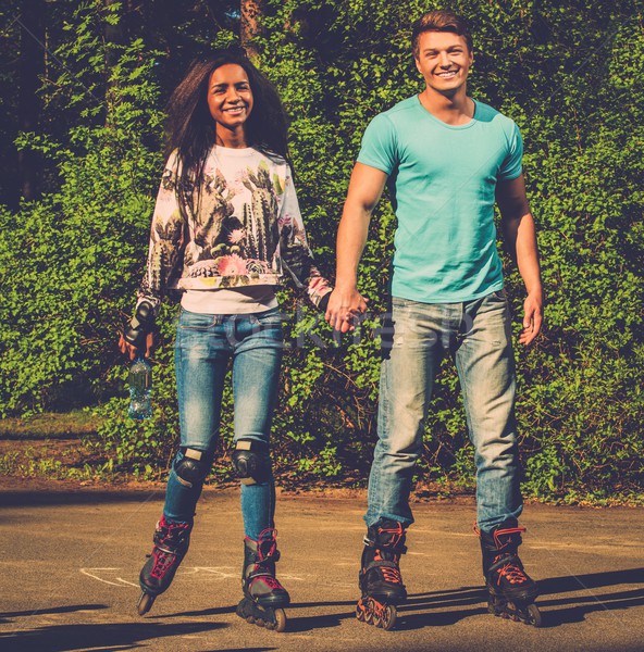 Multi ethnic teenage couple on a rollerblades in a park  Stock photo © Nejron