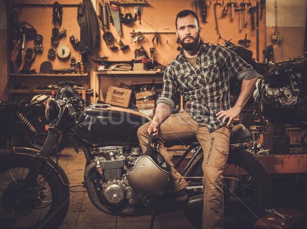 Rider and his vintage style cafe-racer motorcycle in customs garage  Stock photo © Nejron