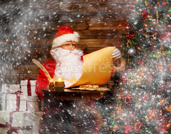 Santa Claus in wooden home interior reading wish list scroll Stock photo © Nejron
