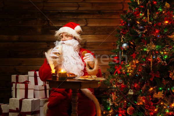 Santa Claus  in wooden home interior with glass of milk and oatmeal cookies Stock photo © Nejron