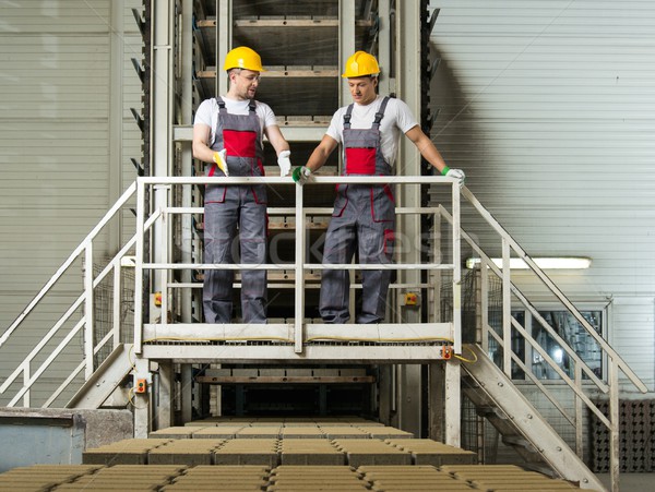 Stock photo: Two men in a safety hats on a factory  