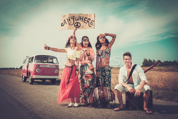 Multi-ethnic hippie hitchhikers with guitar and luggage on a road Stock photo © Nejron