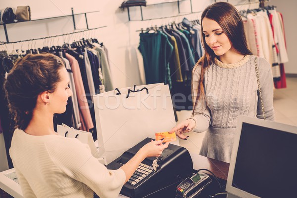 Stock photo: Happy woman customer paying with credit card in fashion showroom