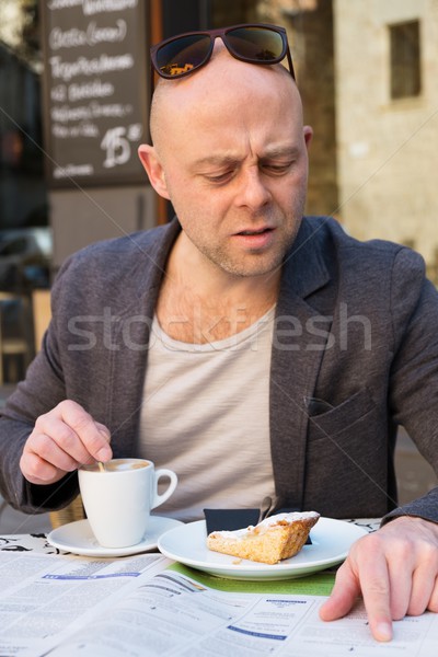 Middle-aged man reading newspaper behind table in street cafe during coffee pause Stock photo © Nejron