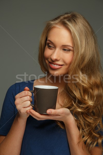 Positive young woman with long hair and blue eyes holding cup Stock photo © Nejron