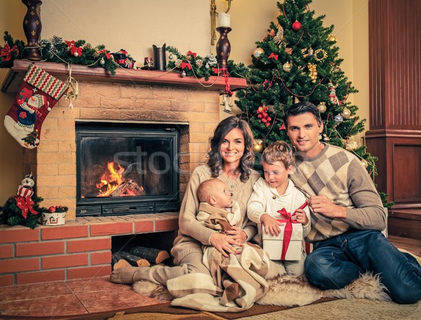 Stock photo: Family near fireplace in Christmas decorated house interior with gift box