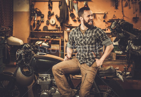 Rider and his vintage style cafe-racer motorcycle in customs garage  Stock photo © Nejron