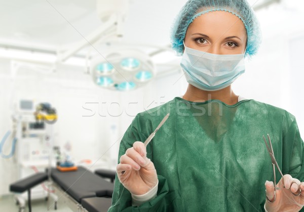 Young woman doctor with scalpel and scissors in surgery room interior  Stock photo © Nejron
