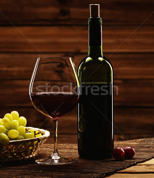 Bottle of red wine, glass and grape in basket in wooden interior  Stock photo © Nejron