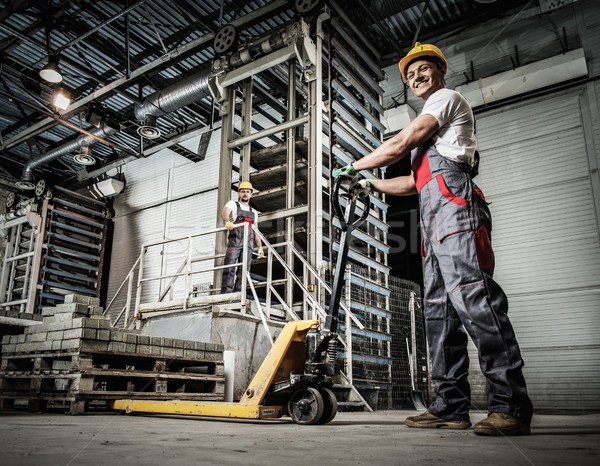 Young worker moving paving stones with pallet truck on a factory Stock photo © Nejron